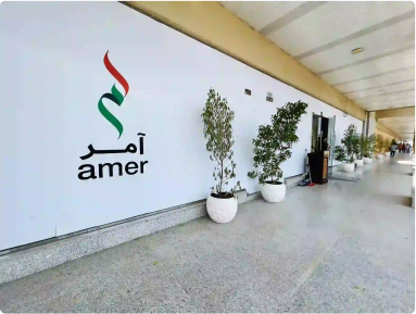 Exterior view of Amer Center entrance with logo and potted plants,

                                showcasing facilities in Dubai.
